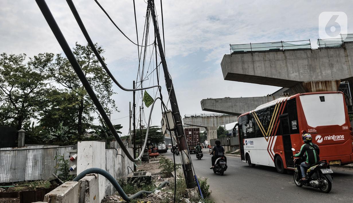 Kendaraan melintas dekat instalasi kabel yang semrawut di Jalan Raya Bekasi, Cakung, Jakarta, Rabu (30/9/2020). Minimnya perawatan pascapembebasan lahan permukiman untuk proyek Tol Dalam Kota membuat jaringan kabel listrik di sepanjang jalan tersebut semrawut. (merdeka.com/Iqbal S. Nugroho)