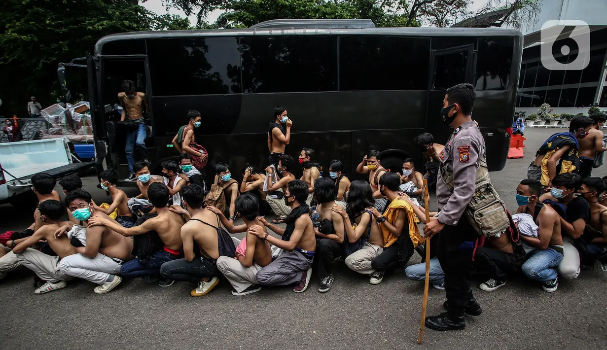 Sejumlah pemuda diamankan di Lapangan Futsal Gedung DPR, Kompleks, Parlemen, Senayan, Jakarta, Kamis (8/10/2020). Ratusan pemuda yang diamankan oleh petugas ini diduga hendak ikut demonstrasi menolak pengesahan Rancangan Undang-Undang Cipta Kerja menjadi UU di gedung DPR. (Liputan6.com/Johan Tallo)