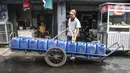 Pedagang mengantarkan air pikulan kepada warga di kampung nelayan Kalibaru, Cilincing, Jakarta Utara, Selasa (22/3/2022). Hingga kini air pikulan masih menjadi kebutuhan utama warga di kawasan pesisir Cilincing untuk keperluan konsumsi akibat air sumur keruh dan bau. (merdeka.com/Iqbal S Nugroho)