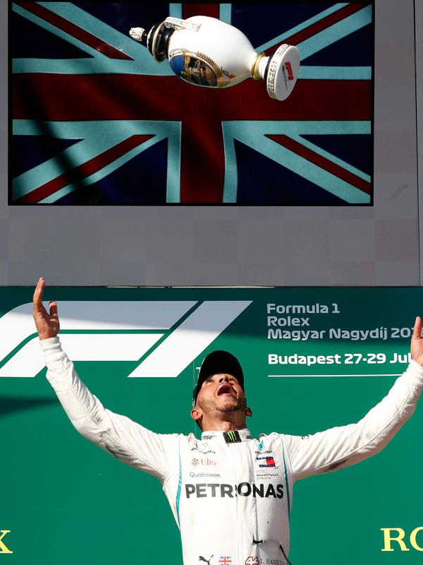 Pembalap Mercedes, Lewis Hamilton berselebrasi setelah berhasil menjuarai GP Hungaria di Sirkuit Hungaroring, Mogyorod, (29/7). Hamilton berhasil menjaga selisih 24 poin dari pesaing terdekatnya, pebalap Ferrari, Sebastian Vettel. (AP Photo/Laszlo Balogh)