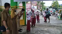 Peserta didik baru diantar orang tua dan disambut penuh hangat oleh guru setibanya di sekolah. (Liputan6.com)