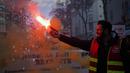 Demonstran dari serikat pekerja CGT yang mengenakan jaket pekerja kereta api memegang suar selama pawai protes, di Lyon, Prancis tengah, Paris, Selasa (31/1/2023). Unjuk rasa yang disertai aksi mogok massal ini diprediksi melumpuhkan sistem transportasi Prancis, terutama kereta. (AP Photo/Laurent Cipriani)