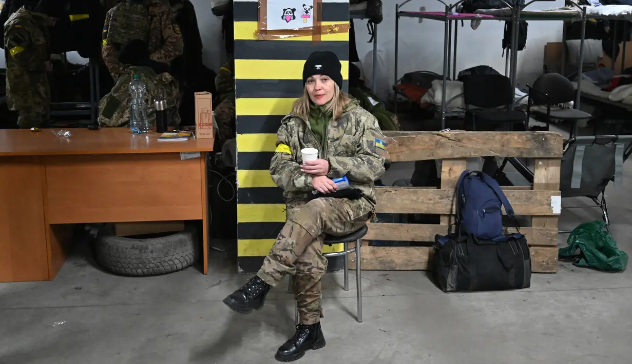 Seorang prajurit wanita Pasukan Pertahanan Teritorial Ukraina, cadangan militer Angkatan Bersenjata Ukraina, minum teh di garasi bawah tanah yang telah diubah menjadi pangkalan pelatihan dan logistik di Kiev, pada Jumat (11/3/2022). (Sergei SUPINSKY / AFP)