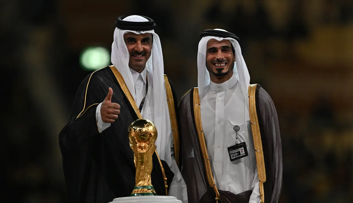 Sheikh Jassim Bin Hamad Al-Thani (kanan) bersama saudaranya Sheikh Tamim bin Hamad al-Thani dari Qatar) berpose di atas panggung dengan trofi Piala Dunia pada akhir pertandingan final Piala Dunia Qatar 2022 antara Argentina dan Prancis di Stadion Lusail di Lusail, utara Doha pada 18 Desember 2022. (AFP/Paul Ellis)