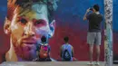 Mural bergambar wajah bintang Barcelona, Lionel Messi, menjadi daya tarik bagi warga di Barcelona, Catalonia, Sabtu (17/6/2017). (AFP/Josep Lago)