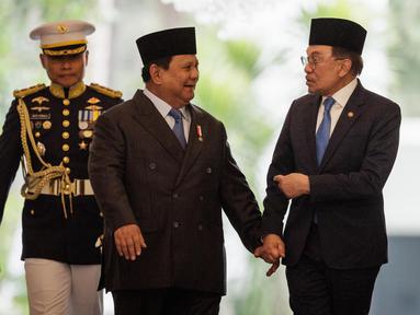 Presiden Republik Indonesia Prabowo Subianto (tengah) dan Perdana Menteri Malaysia Anwar Ibrahim (kanan) berjalan bersama menjelang pertemuan bilateral di Istana Kepresidenan, Jakarta pada 29 Juli 2025. (Yasuyoshi CHIBA/AFP)