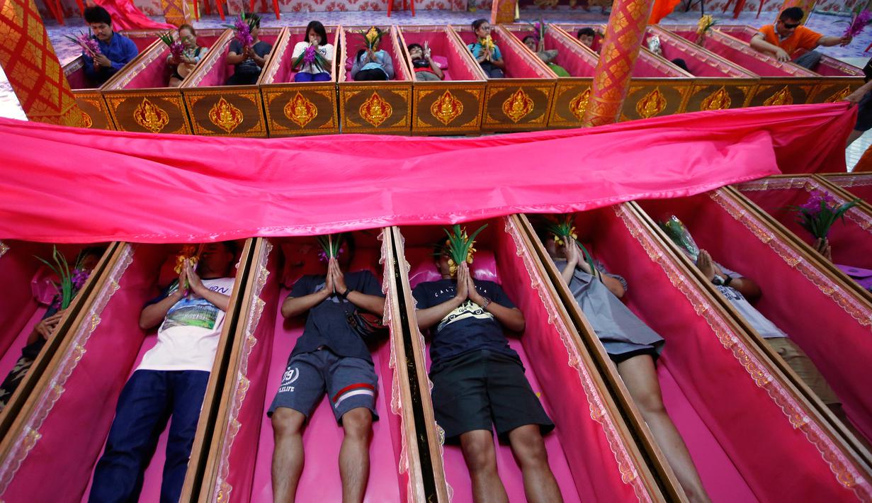 Sejumlah pemuja berdoa dalam peti mati di kuil Takien, pinggiran kota Bangkok, Thailand, Senin (31/12). Mereka mempercayai ritual ini dapat membantu menyingkirkan nasib buruk dan dianggap sebagai awal dari kehidupan baru. (AP/Sakchai lalit)