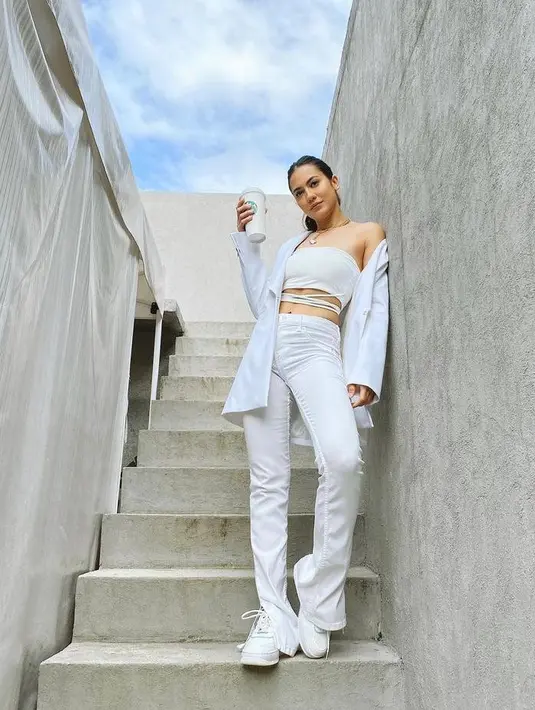 Tampil serba putih, perempuan 29 tahun ini kali ini tampil memadukan tie waist crop top dengan blazer dan celana panjang warna senada. Tak lupa, ia memakai high up sneakers yang membuat tampilannya makin sempurna. (Instagram/pevpearce).