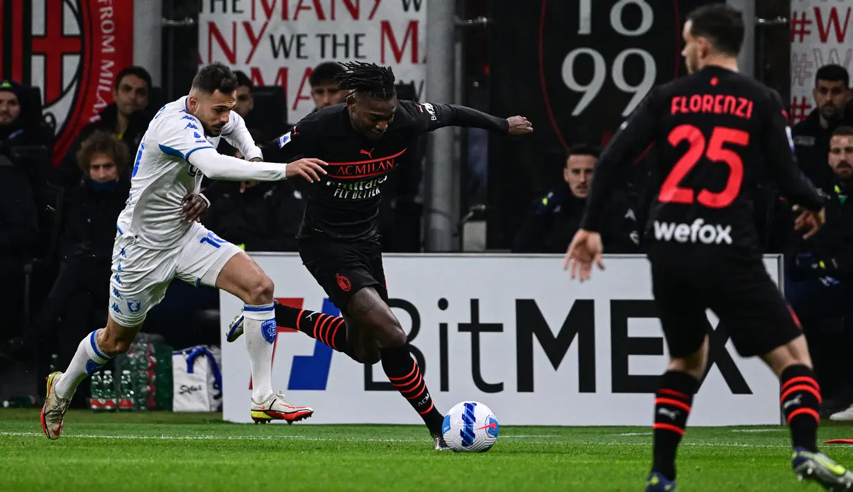 Penyerang AC Milan Rafael Leao (tengah) berebut bola dengan gelandang Empoli Nedim Bajrami pada pekan ke-29 Liga Italia di Stadion San Siro, Minggu (13/3/2022) dini hari WIB.  AC Milan menang tipis 1-0 atas tamunya, Empoli. (Miguel MEDINA / AFP)