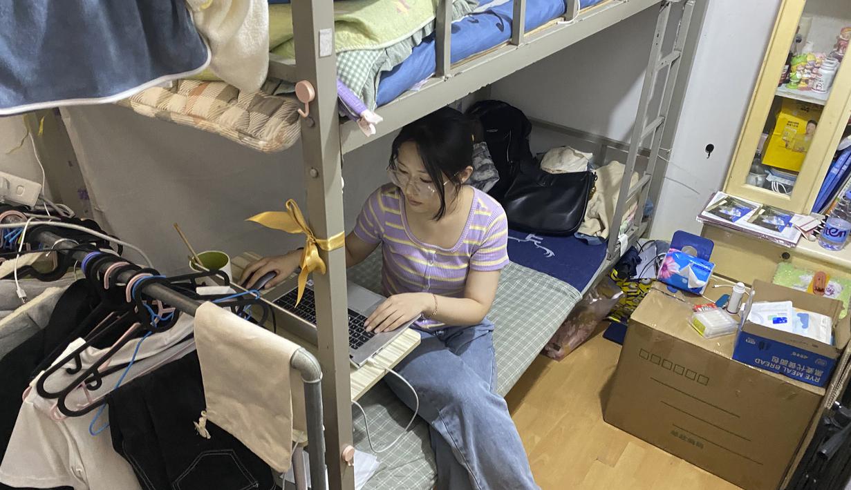 Lulusan perguruan tinggi baru-baru ini Liu Qian bekerja di komputer laptopnya di kamar yang dia sewa di sebuah apartemen di Beijing, Kamis, 7 Juli 2022.  Liu adalah salah satu dari 11 juta lulusan baru yang putus asa untuk bekerja di pasar kerja yang suram karena lockdown COVID memaksa pabrik, restoran, dan pengusaha lainnya untuk tutup. Para penyintas memotong pekerjaan dan upah. (AP Photo/Olivia Zhang)
