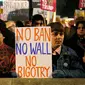 Demonstran membentangkan poster saat unjuk rasa di luar Downing Street, London, Senin (30/1). Mereka memprotes kebijakan Presiden AS Donald Trump yang melarang Muslim dari sejumlah negara memasuki Amerika Serikat. (AP Photo/Alastair Grant)