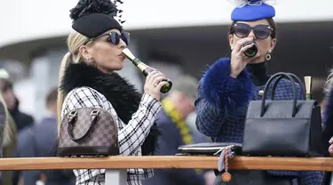 Dua wanita menikmati sampanye pada hari pertama Festival Cheltenham di Cheltenham Racecourse, Inggris, Selasa (15/3/2022). Kehadiran para wanita memberikan nuansa tersendiri di kompetisi pacuan kuda tersebut. (Mike Egerton/PA via AP)