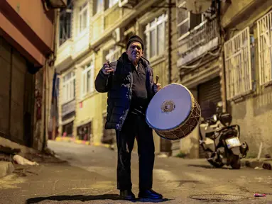 Penabuh gendang Turki, Hakan Ozbingol, memainkan gendang dan menyanyikan lagu-lagu tradisional di jalanan Istanbul, untuk membangunkan umat Muslim untuk sahur, yaitu makan malam Ramadan, pada 24 Februari 2026. Turki memiliki tradisi menabuh drum di jalan-jalan untuk membangunkan sahur sebelum memulai puasa di bulan suci Ramadan. (Yasin AKGUL/AFP)