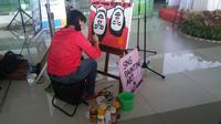 Seorang pelukis, ikut menyambut kedatangan Tontowi Ahmad/Liliyana Natsir di Bandara Soekarno-Hatta, Indonesia. (Bola.com/Yus Mei Sawitri)