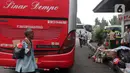 Seorang pria berjalan dibelakang bus di Terminal Kampung Rambutan, Jakarta, Selasa (21/12/2021). Kepala Terminal Kampung Rambutan Yulza Ramadhoni mengatakan, penumpang bus meningkat 10 persen menjelang Natal 2021 dan Tahun Baru 2022. (Liputan6.com/Hermann Zakharia)