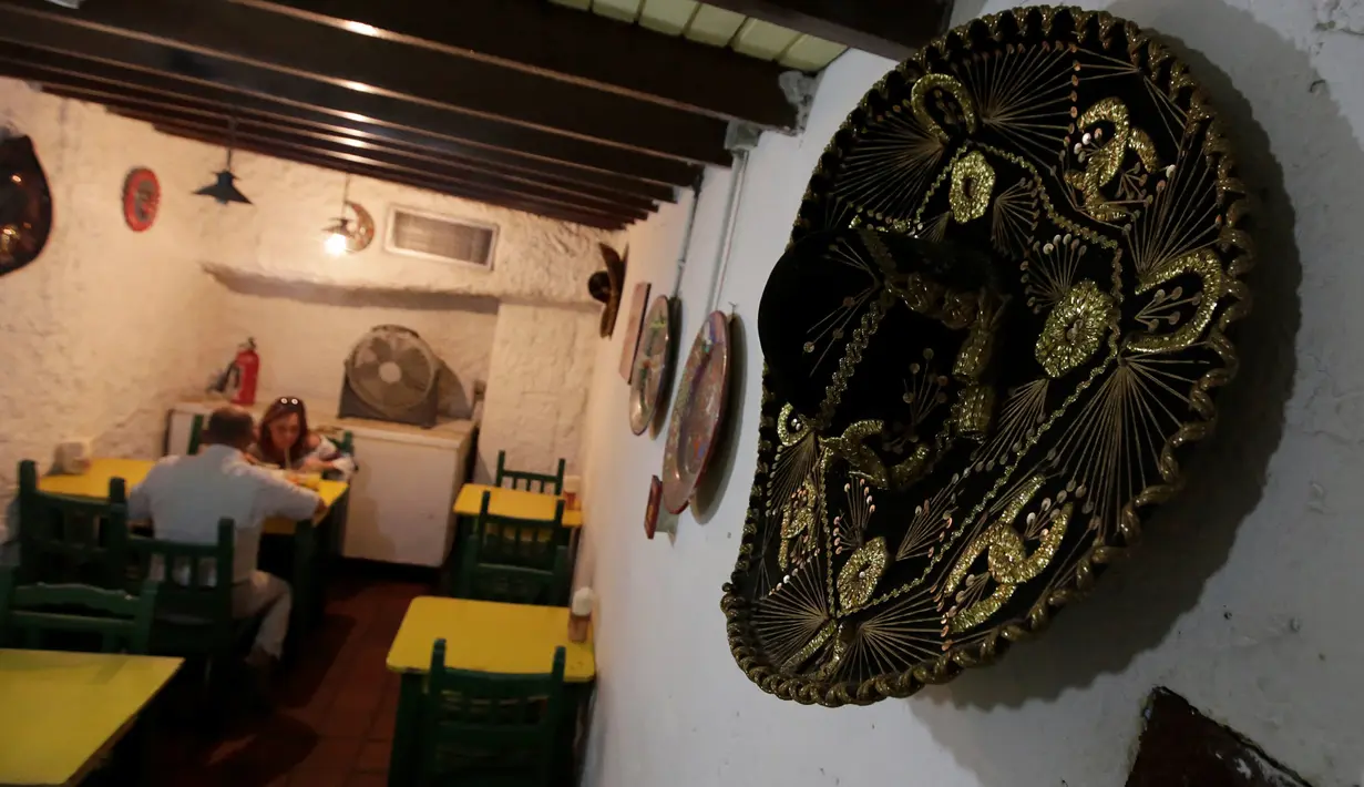 Sepasang pelanggan sedang menikmati makanan di restoran El Tizoncito, Caracas, 13 September 2016. Karena krisis ekonomi di Venezuela, restoran ini menawarkan seporsi makanan yang bisa ditukar dengan 2 liter minyak goreng. (REUTERS/Henry Romero)