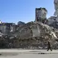 Seorang pria berjalan melewati bangunan yang  hancur di Salaheddine, Aleppo, Suriah, 20 Januari 2018. Gejolak krisis ekonomi menyebabkan lonjakan harga makanan dan kebutuhan dasar di Suriah. (12/6/2020). (AP Photo/Hassan Ammar, File)