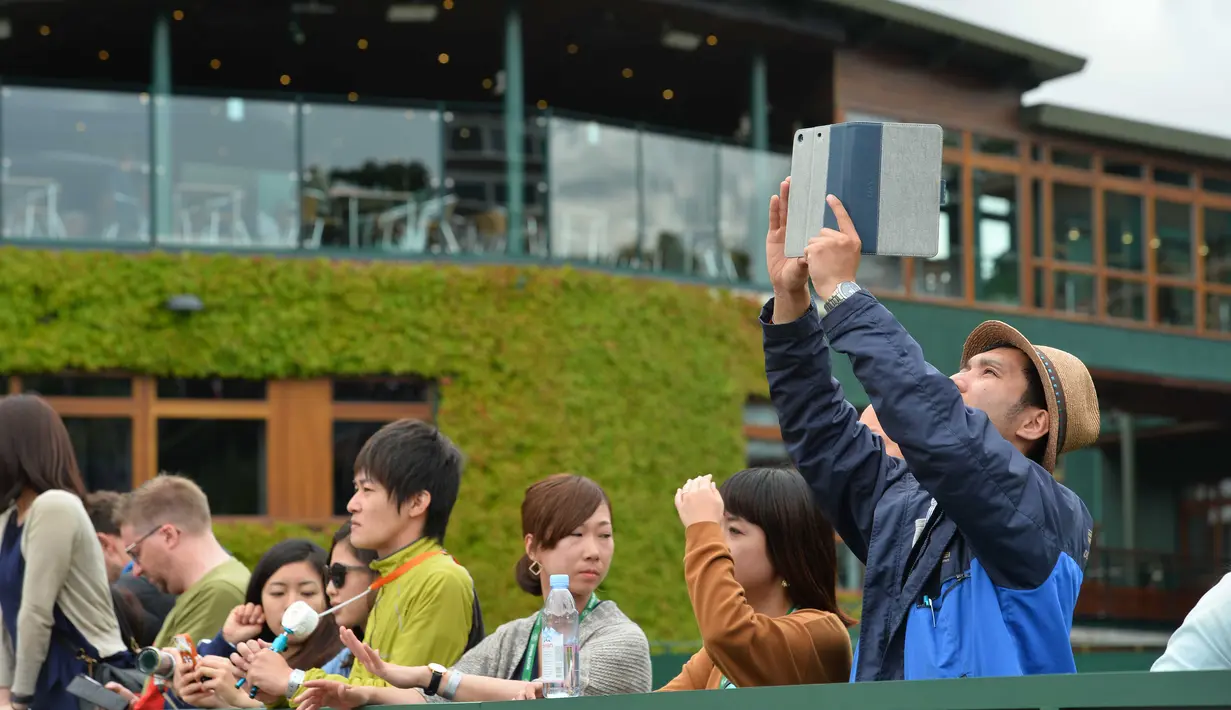 Penonton mengambil gambar suasana lapangan sebelum menonton Tenis Wimbledon Championships 2016 di The All England Lawn Tennis Club, Wimbledon,  London, (27/6/2016). (AFP/Glyn Kirk)