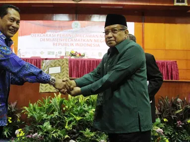 Ketua Umum PBNU KH Said Aqil Siradj memberikan laporan hasil deklarasi kepada Kepala BNN, Budi Waseso saat acara  Lembaga Persahabatan Ormas Islam deklarasi melawan Narkoba demi menyelamatkan Negara di Jakarta, Kamis (22/12). (Liputan6.com/Johan Tallo)