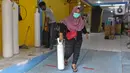 Warga berjalan keluar usai mengisi ulang oksigen di Fauzi Medical, Matraman, Jakarta Timur, Kamis (22/7/2021). Sebagai bentuk kepedulian terhadap sesama di tengah pandemi COVID-19, agen isi ulang oksigen tersebut menerapkan sistem pembayaran secara sukarela bagi warga. (Liputan6.com/Herman Zakharia)