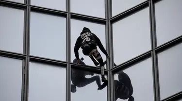 Pendaki Alain Robert atau French Spiderman memanjat Menara Total di kawasan bisnis La Defense, Paris, Prancis, Senin (13/1/2020). Alain memanjat gedung 48 lantai tersebut sebagai dukungan untuk pekerja yang mogok karena menentang reformasi pensiun di Prancis. (Thomas SAMSON/AFP)