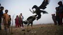 Anak-anak menonton pertandingan sabung ayam di pinggiran Islamabad, Pakistan, 15 Desember 2021. Pakistan terkenal memiliki jenis ayam petarung paling tua di dunia dengan kekuatan fisik dan mental bertarungnya. (AP Photo/Rahmat Gul)