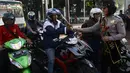 Para pengendara motor di kawasan Slipi mendapat bunga dari seorang Polwan, Jakarta, Selasa (21/4/2015). Pembagian bunga ini dalam rangka memperingati hari Kartini.(Liputan6.com/Johan Tallo)