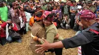 Sejumlah warga menyaksikan aksi dua pegulat tradisional (gulat okol), usai upacara Sedekah Bumi Kelurahan Made kecamatan Sambi Kerep, Surabaya, di Taman Bungkul Surabaya. (Antara)