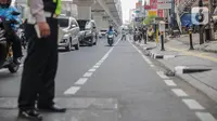 Petugas satlantas mensterilkan jalur sepeda di kawasan Blok A, Jakarta, Senin (25/11/2019). Mulai hari ini, polisi akan menilang para pengendara kendaraan bermotor yang nekat masuk dan melintas di jalur sepeda. (Liputan6.com/Faizal Fanani)