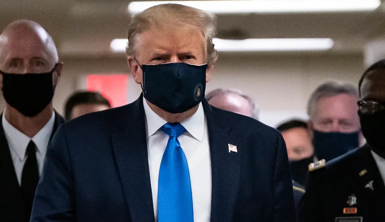 Presiden Amerika Serikat Donald Trump mengenakan masker saat mengunjungi Pusat Kesehatan Militer Nasional Walter Reed di Bethesda, Maryland, Sabtu (11/7/2020). Donald Trump akhirnya menggunakan masker untuk pertama kalinya di depan umum sejak pandemi COVID-19 melanda negara itu.  (ALEX EDELMAN/AFP)