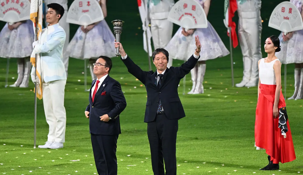 Gubernur di prefektur Aichi, Jepang, Ohmura Hideaki (kiri) dan wakil walikota Nagoya, Jepang, Nakata Hideo (kanan) mengambil bagian dalam penyerahan obor pada upacara penutupan Asian Games 2022 yang berlangsung di Hangzhou Olympic Sports Centre Stadium, Hangzhou, China pada Minggu (08/10/2023). Jepang menjadi tuan rumah Asian Games selanjutnya yang akan berlangsung pada 2026 mendatang. (AFP/Jung Yeong-je)