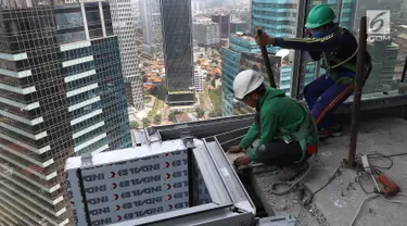 Pekerja Nusa Konstruksi Enjiniring memasang kaca gedung World Capital Tower, di Mega Kuningan, Jakarta, Rabu (13/9). Deretan gedung perkantoran masih menghiasi di ibukota Jakarta. (Liputan6.com/Fery Pradolo)