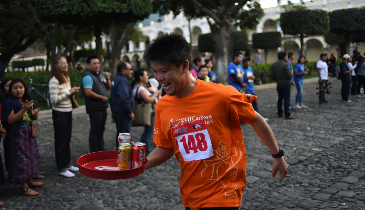 Seorang pramusaji beradu kecepatan sambil membawa nampan dalam Waiters Race ke-16 di Antigua, barat daya Ibu Kota Guatemala City, Rabu (14/11). Lomba ini diikuti oleh ratusan peserta yang merupakan pelayan restoran dan kafe setempat. (JOHAN ORDONEZ/AFP)