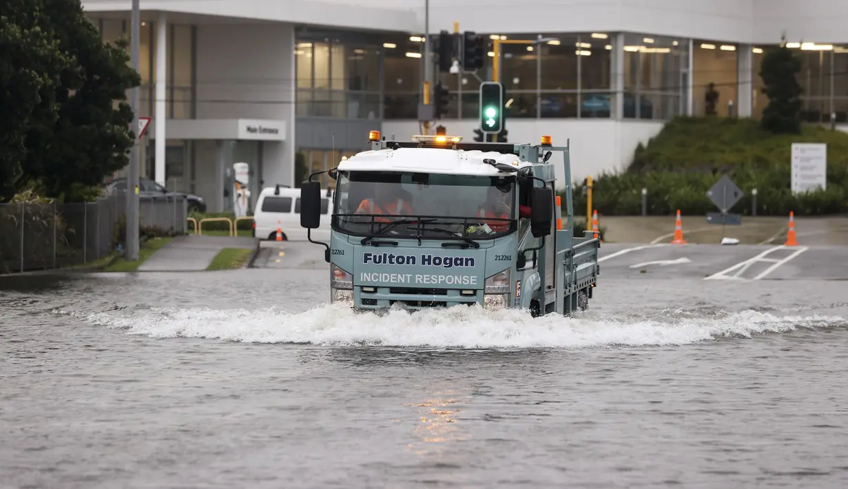 Para pria mengendarai truk melewati air banjir di Auckland, Selandia Baru, Rabu (1/2/2023). Peringatan hujan lebat untuk Auckland dicabut, meskipun keadaan darurat tetap berlaku untuk kota terbesar di negara itu setelah curah hujan dan banjir yang mencapai rekor. pada hari Jumat menewaskan empat orang dan menyebabkan gangguan yang meluas. (Brett Phibbs/New Zealand Herald via AP)