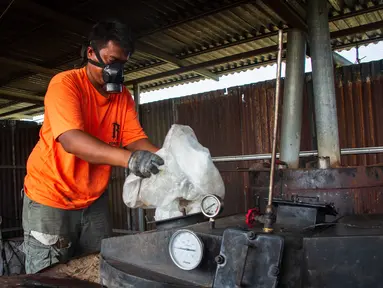 Pekerja memasukkan kantong plastik ke dalam mesin pengolah untuk memproduksi Petasol dalam sebuah lokakarya di Pekanbaru, Riau, pada 8 Agustus 2025. (Wahyudi/AFP)