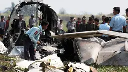 Petugas memeriksa puing pesawat militer yang jatuh sesaat setelah lepas landas di bandara Kota Naypidaw, Myanmar, Rabu (10/2). Pesawat penumpang jenis Beechcraft tersebut sedang membawa lima orang kru militer yang akan melakukan patroli rutin. (STR/AFP)