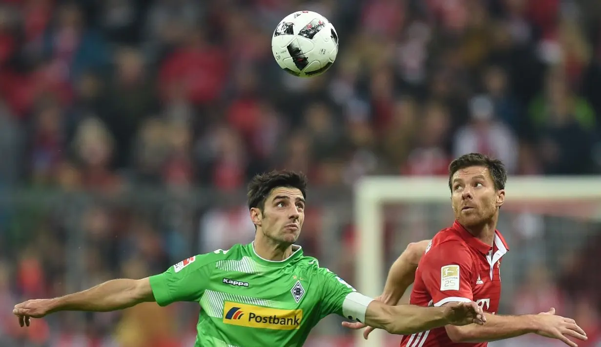 Pemain Bayern Munchen, Xabi Alonso (kanan), berebut bola dengan pemain Borussia Monchengladbach, Lars Stindl, dalam laga pekan ke-8 Bundesliga 2016-2017, Sabtu (23/10/2016). (AFP/Christof Stache)