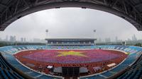 Para peserta mengangkat kain warna-warni untuk membentuk bendera Vietnam selama acara yoga massal di Stadion Nasional My Dinh di Hanoi pada 12 Agustus 2023. (Tien TUAN/AFP)