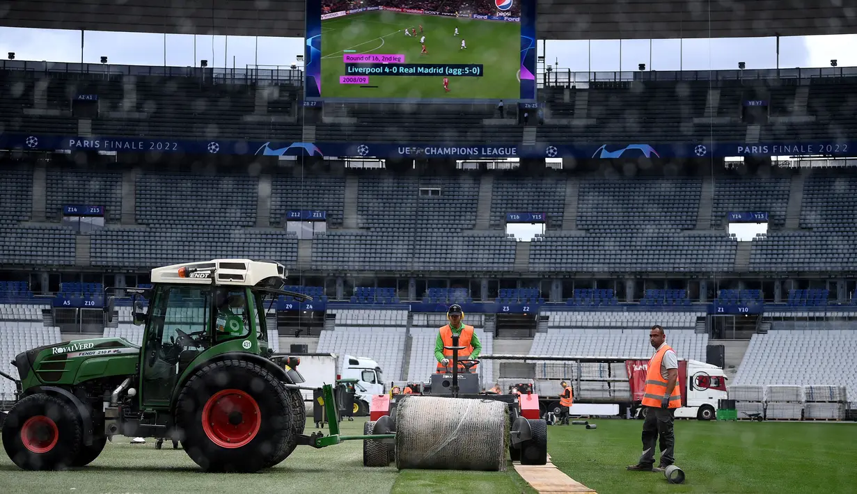 Sejumlah pekerja sedang memasang rumput hybrid baru di Stade de France, Saint-Denis, pada 24 Mei 2022 waktu setempat. Dalam waktu 48 jam, rumput baru yang ditanam di luar Barcelona, dipasang di Stade de France untuk pertandingan final Liga Champions antara Real Madrid dan Liverpool yang dijadwalkan berlangsung pada 28 Mei 2022. (AFP/Franck Fife)