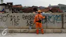 Tembok di sisi tanggul Kali Ciliwung dicat kembali oleh petugas, Jakarta, Selasa (11/10). Aksi vandalisme oleh oknum remaja ini membuat fasilitas publik terlihat kotor. (Liputan6.com/Gempur M Surya)