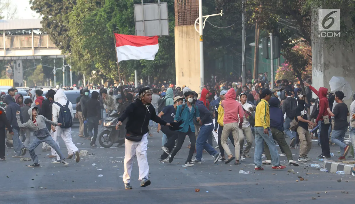 Massa melempar batu ke arah polisi yang membentuk barikade dengan tameng di sekitaran Gedung DPR RI, Jakarta, Senin (30/9/2019). Kericuhan pecah lantaran massa yang kebayakan terdiri dari pelajar tersebut berusaha masuk ke area depan DPR. (Liputan6.com/Angga Yuniar)