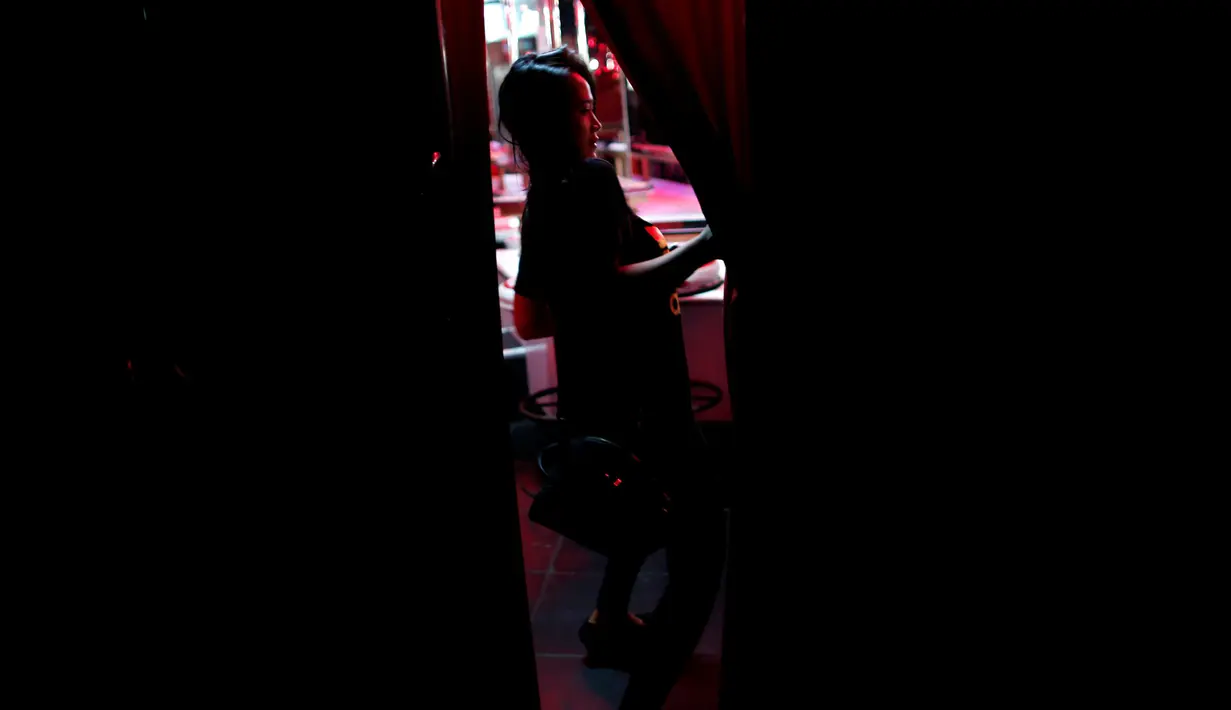 Seorang wanita berada di tempat hiburan malam yang tutup di sebuah kawasan prostitusi atau red-light district, Bangkok, Thailand, (17/10). Beberapa acara di Thailand banyak yang dibatalkan selama masa berkabung. (REUTERS/Issei Kato)