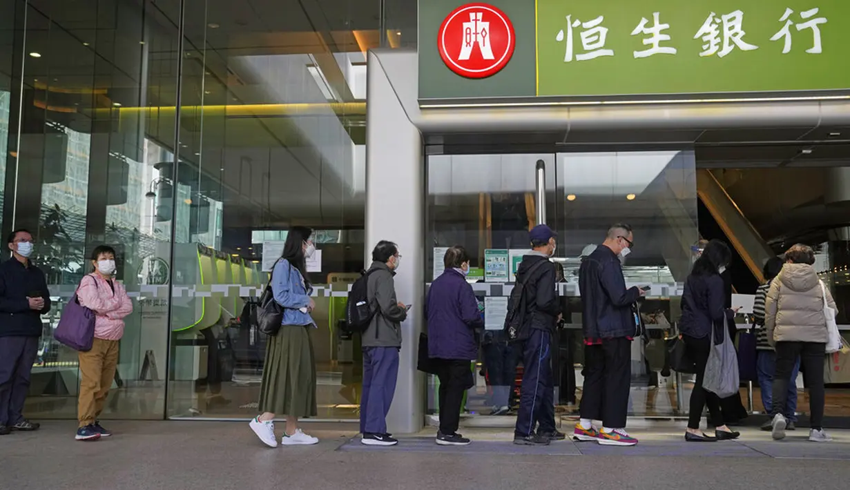 Orang-orang yang memakai masker berbaris di luar sebuah bank di Hong Kong, 8 Maret 2022. COVID-19 varian Omicron yang menyebar cepat membanjiri Hong Kong serta mendorong pengujian massal, karantina, pembelian panik di supermarket, dan rumah sakit kekurangan tempat tidur. (AP Photo/Kin Cheung)