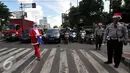 Petugas Kepolisian bersama sinterklas saat membagikan bunga dan masker di jalan kawasan Tomang, Jakarta, Rabu (23/12). Menyambut Hari Natal 2015, anggota Kepolisian Polres Jakarta Barat kenakan topi Sinterklas. (Liputan6.com/Yoppy Renato)