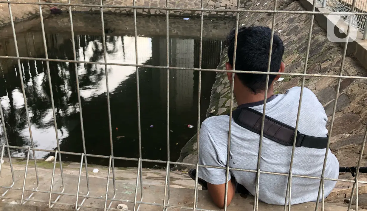 Warga memancing ikan di kubangan yang berada di Jalan DI Panjaitan, Jatinegara, Jakarta, Selasa (16/6/2020). Meski telah dipagari, sejumlah warga tetap memancing ikan di lokasi yang merupakan saluran pembuangan tersebut. (Liputan6.com/Immanuel Antonius)