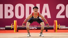Atlet angkat besi Indonesia, Muhammad Husni berkompetisi pada nomor angkat besi putra 55 kg SEA Games 2023 di Taekwondo Hall Olympic Complex, Phnom Penh, Kamboja, Sabtu (13/05/2023). Husni berhasil meraih medali perunggu setelah melakukan total angkatan 233 kg, dengan rincian 133 kg snatch dan 120 clean & jerk. (Bola.com/Abdul Aziz)