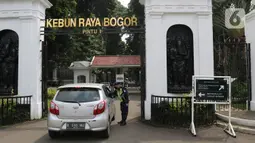 Petugas keamanan memeriksa pengunjung di Kebun Raya Bogor, Jawa Barat, Selasa (7/7/2020). Kebun Raya Bogor menerapkan pemesanan tiket secara daring serta kapasitas pengunjung dibatasi hanya 50 persen. (Liputan6.com/Herman Zakharia)