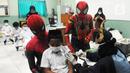 Murid SD dipangku Spiderman saat disuntik vaksin COVID-19 dosis kedua di Sekolah Al-Azhar, BSD, Tangerang Selatan, Banten, Senin (17/1/2022). Sebanyak 450 murid divaksin dengan melibatkan tokoh Spiderman untuk menghibur sekaligus menghilangkan rasa takut anak-anak. (merdeka.com/Arie Basuki)