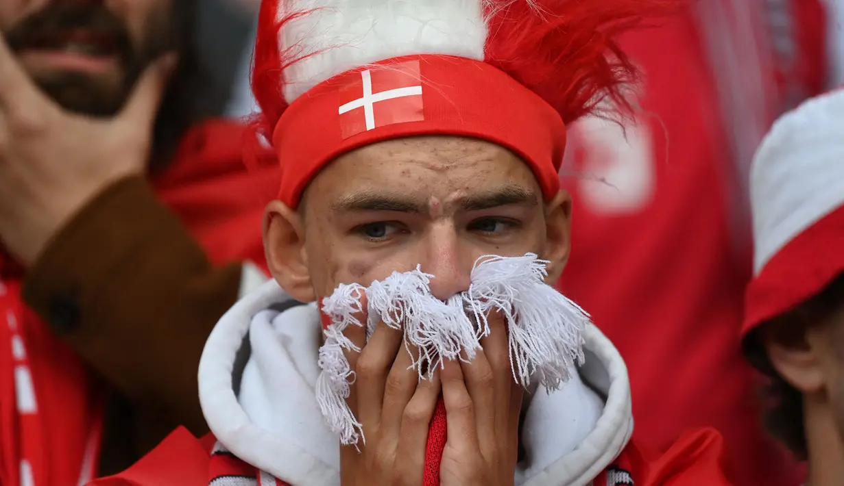 Teriakan dukungan semangat sekejap berubah menjadi raut sedih dan cemas dari pendukung Denmark ketika dikejutkan dengan insiden Christian Eriksen yang tiba-tiba jatuh tak sadarkan diri pada menit ke-43. (Foto: AFP/Pool/onathan Nackstrand)