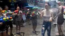 Warga menyemprotkan air ke seorang wanita saat merayakan Festival Songkran atau Tahun Baru Thailand di Bangkok, Thailand, 13 April 2019. Warga Thailand mengisi Festival Songkran dengan bersenang-senang, salah satunya perang air. (Lillian SUWANRUMPHA/AFP)